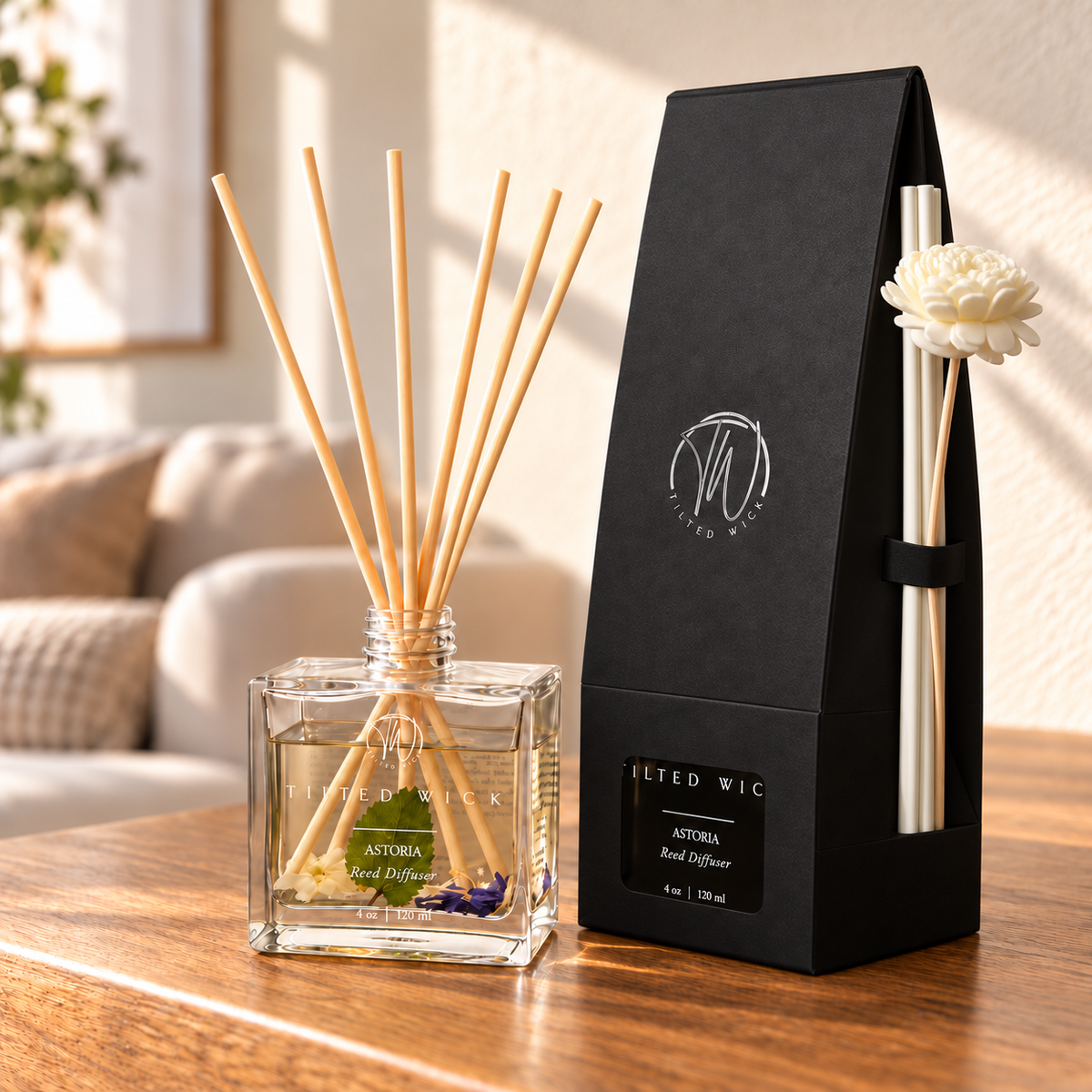 Astoria reed diffuser with long ivory reeds and flower secured on the side of tapered black packaging