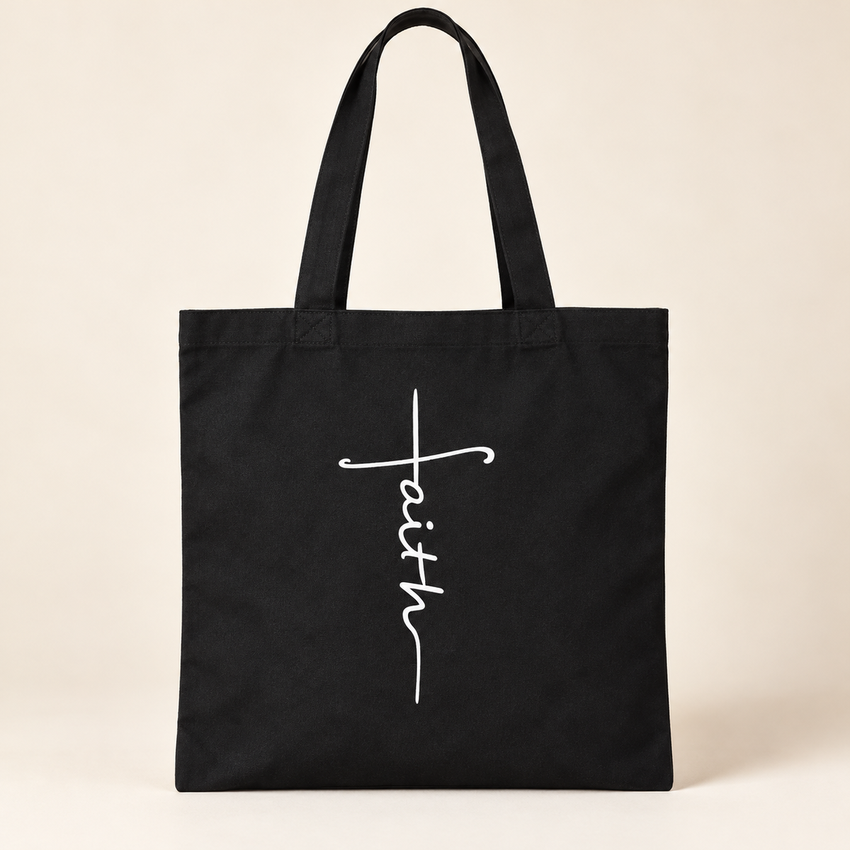 Black canvas Faith tote on a warm ivory background, styled product image