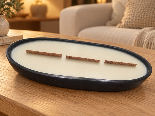 Handmade black concrete candle boat with ivory wax and wooden wicks on an oak coffee table