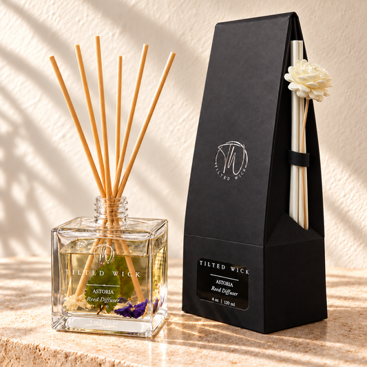 Astoria reed diffuser with long ivory reeds and flower secured on the side of tapered black packaging