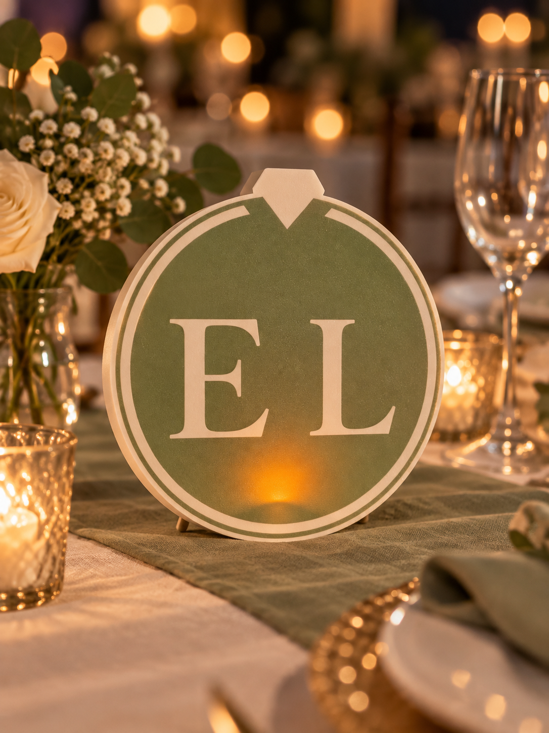 Sage green and ivory E L wedding ring light styled mockup with subtle LED tealight glow near the base